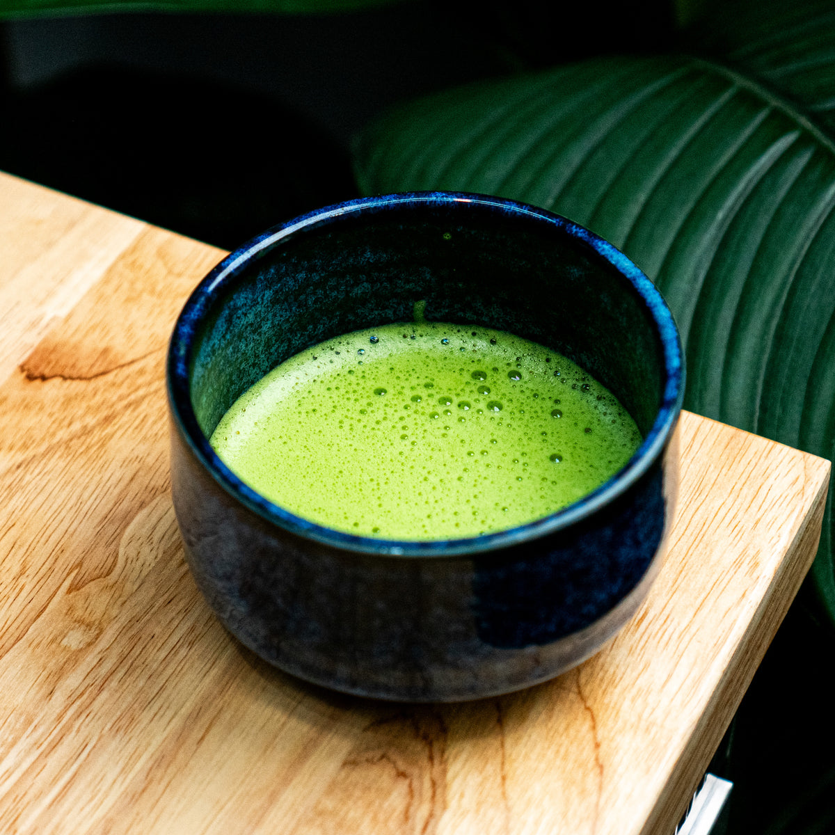 Organic matcha - Japanese Green matcha tea in a blue ceramic bowl on a wooden surface