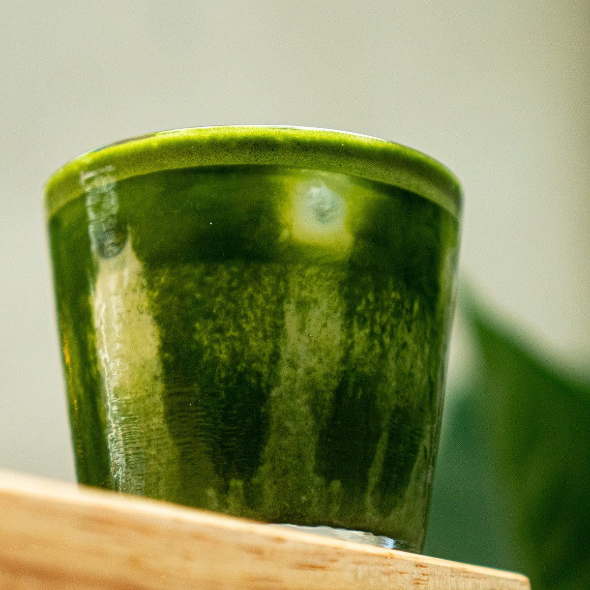 Japanese organic matcha latte iced in cup on a wooden surface with a blurred background
